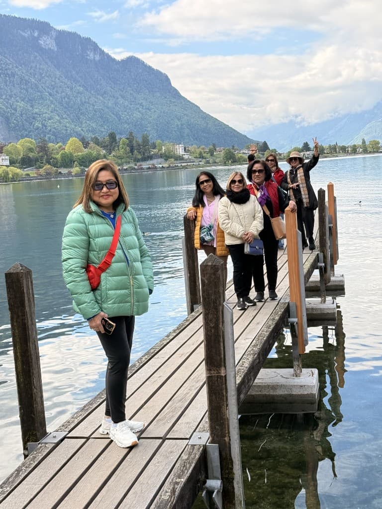 Group of travelers on a lake pier with mountains in the background